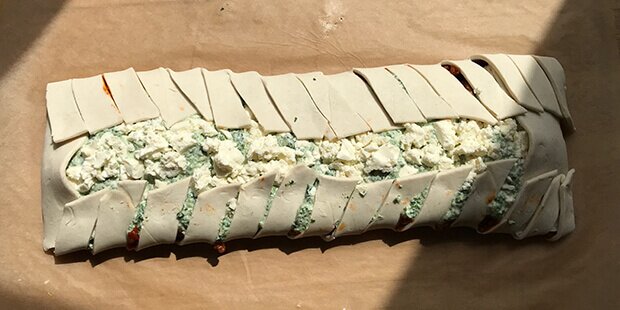 Fold enderne over fyldet i hver ende, og fold dernæst strimlerne langs kanterne indover.