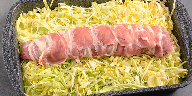 Svinemørbraden er pakket ind i bacon og lagt på porrebunden, så retten er klar til ovnen.