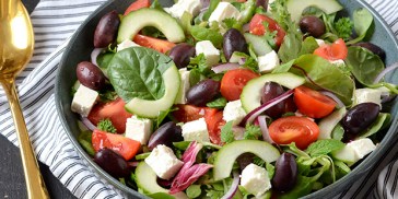 Den grønne salat får selskab af cremet feta og friske tomater.