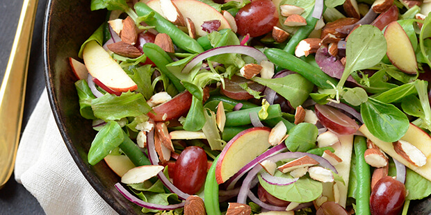 Søde vindruer og æblestykker gør den grønne salat super frisk og lækker.