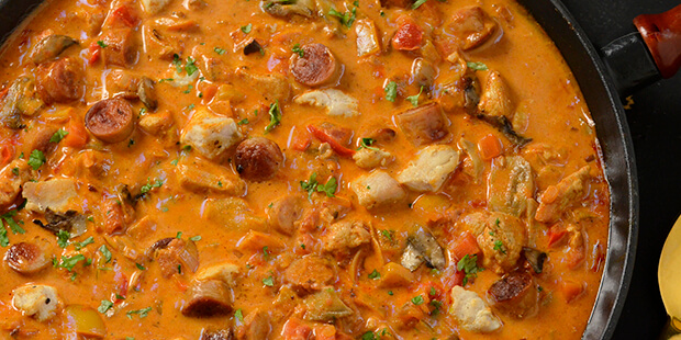 De stegte stykker kylling og pølser omgives af den lækre sovs i gryderetten.